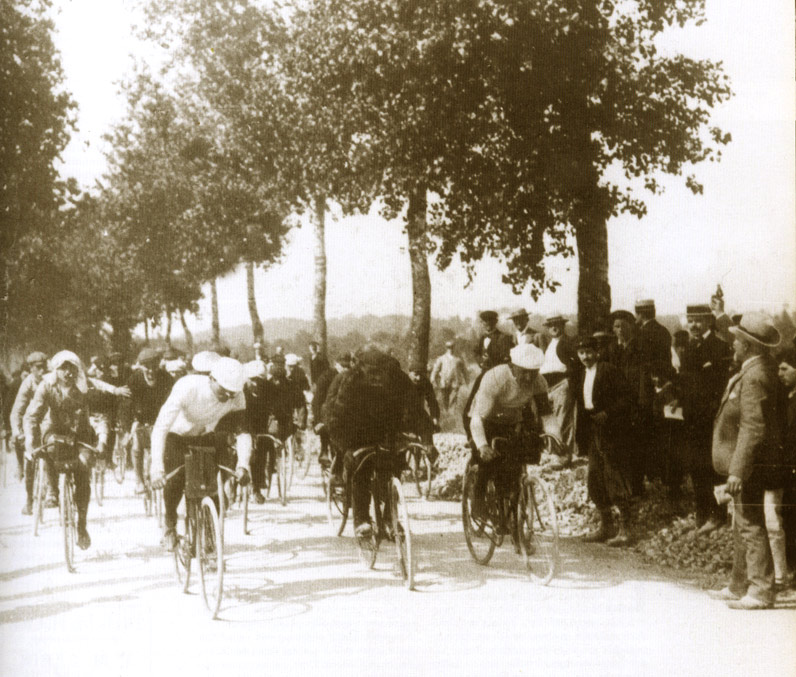 A bunch of cyclists riding their bikes on an unoaved road during the very first stage of the very first Tour de France in 1903