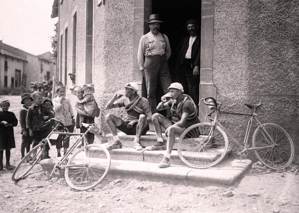 The famous vintage cyclong image of two cyclists drinking beer on the step of a tavern during Tour de France 1921
